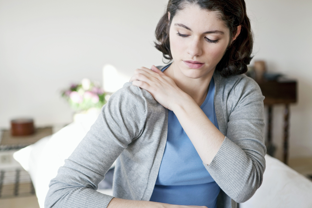 woman holding her shoulder because of shoulder pain